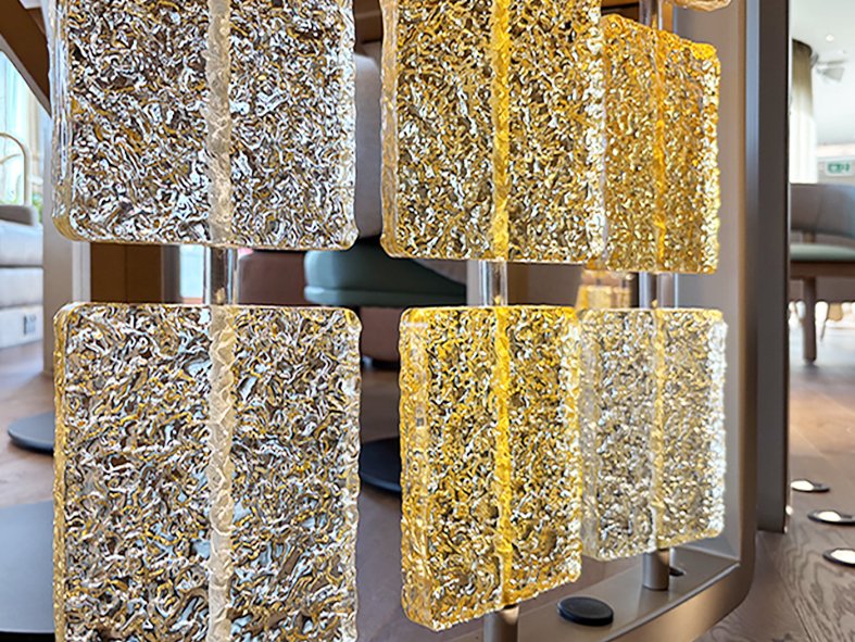 Close-up of amber and clear textured cast glass tiles suspended on slender rods in a BoTree hotel screen